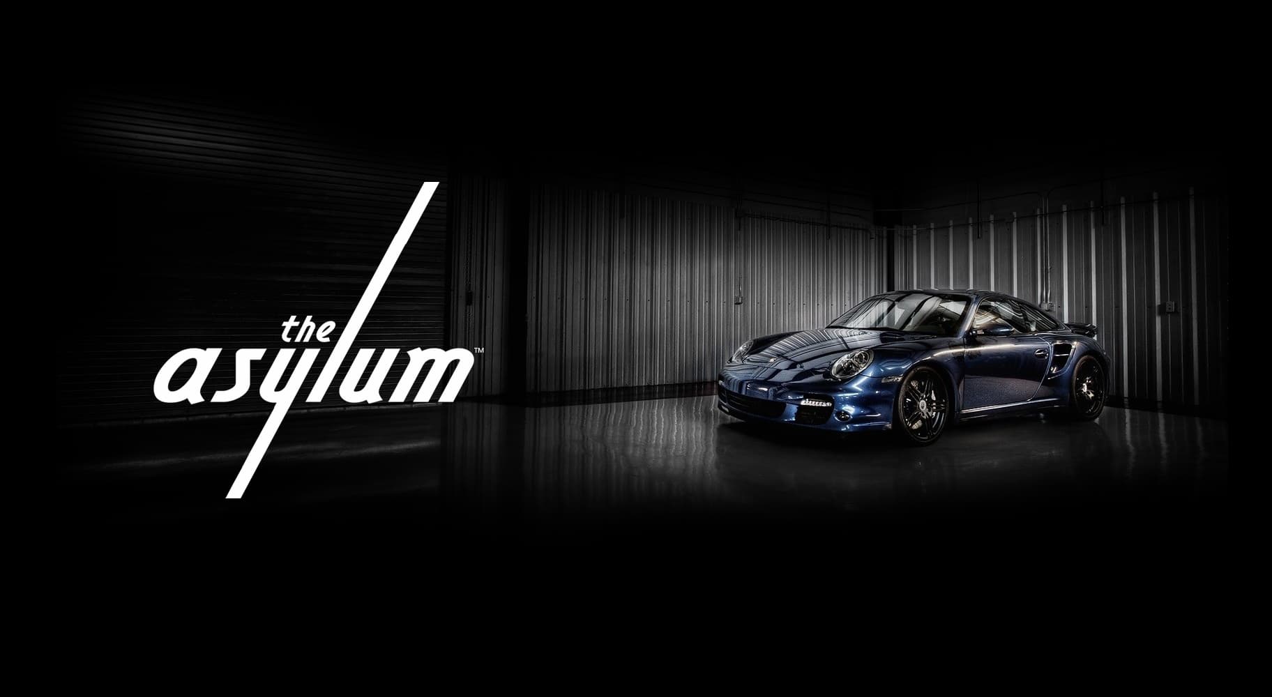 Dark blue Porsche 911 with The Asylum logo at Houston's premier automotive event venue
